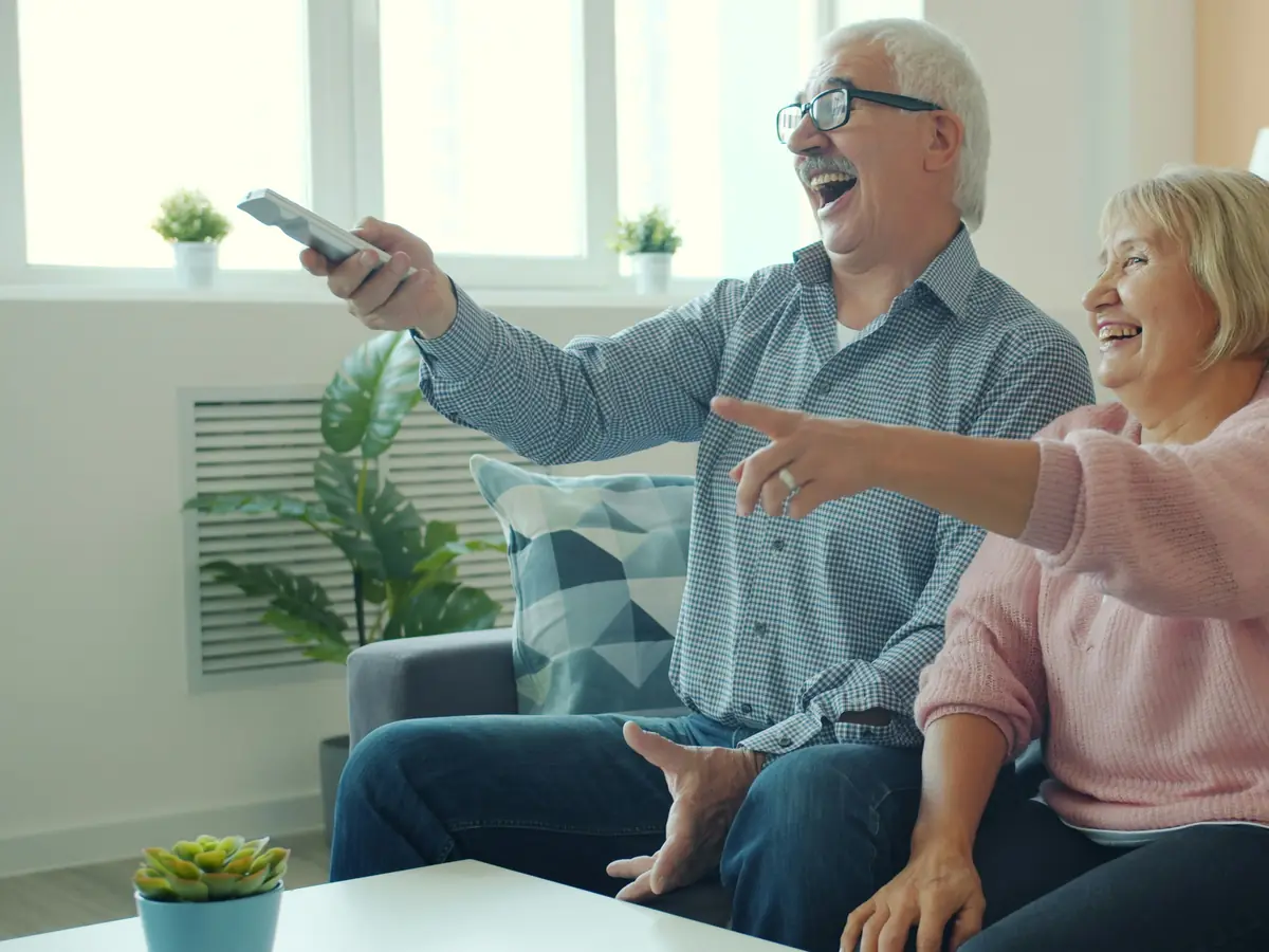 Grandparents laughing while watching television together