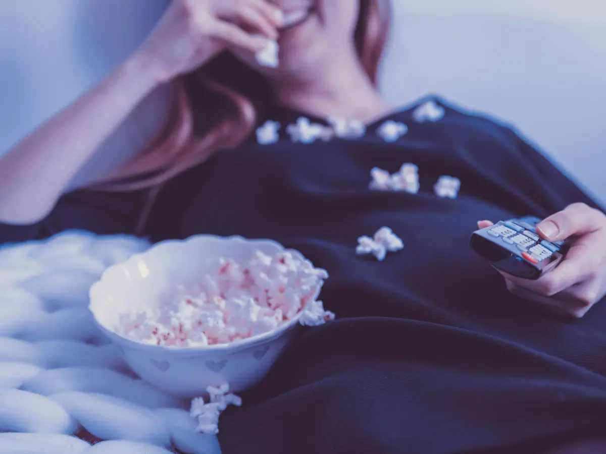 Popcorn and a remote on a sofa during a series night